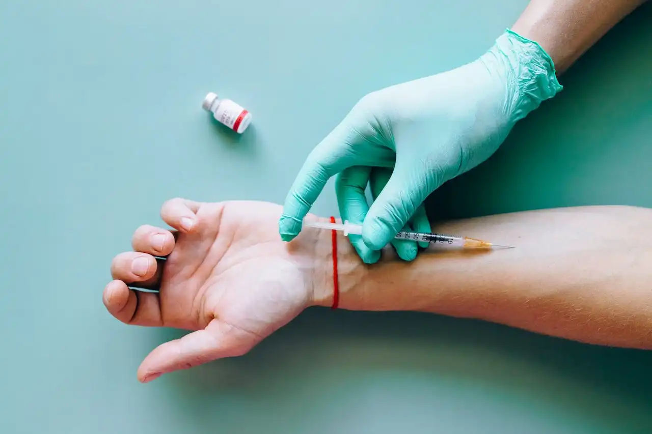 Close-up of a medical syringe being applied to an arm by a gloved hand