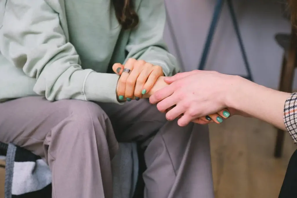 Close-up of two people holding hands during a comforting therapy session