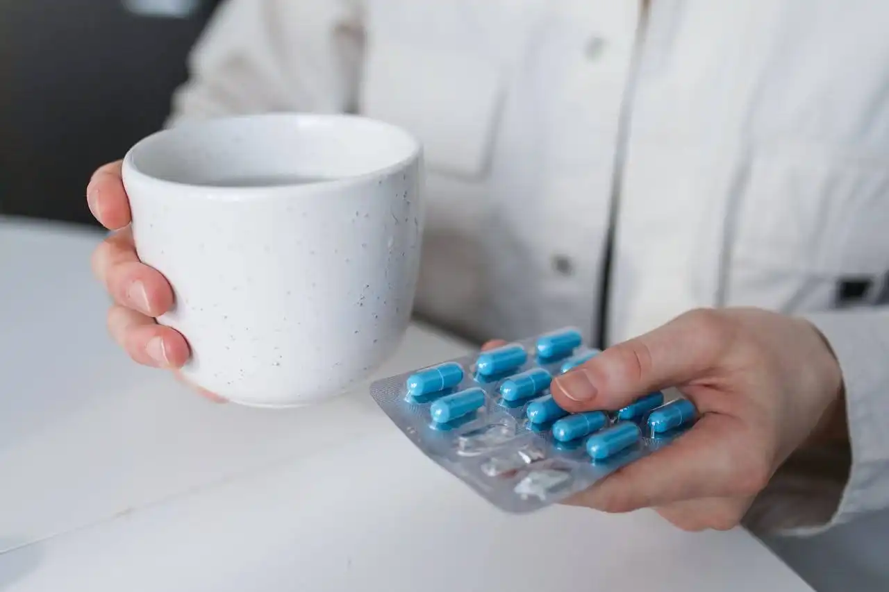 a man holding a cup of water and medicine