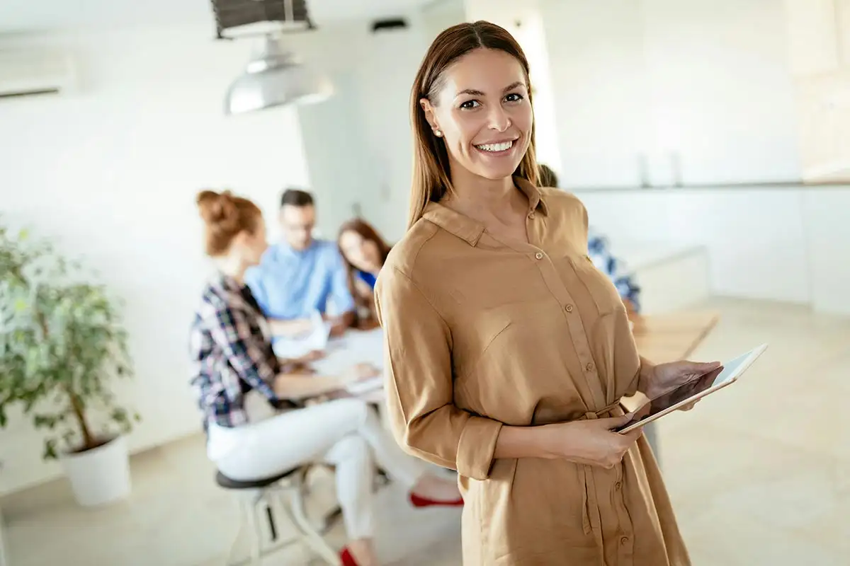 female executive standing smiling for the camera with her team at the back in southern california, riverside