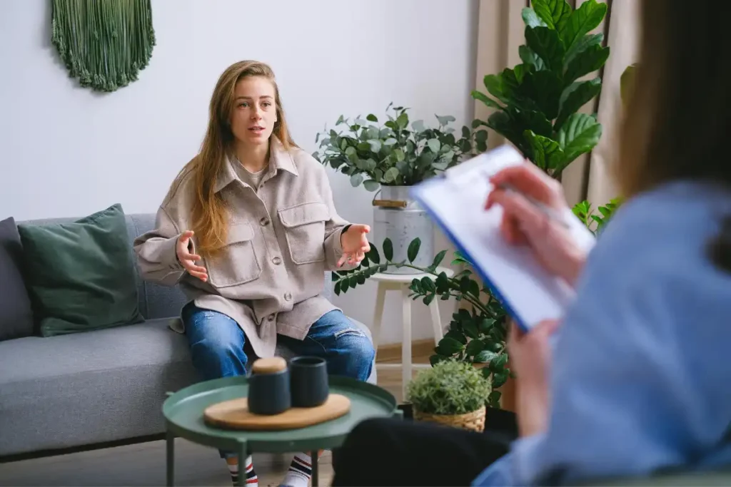 A woman engages in a therapy session, discussing issues with a counselor inside a modern office