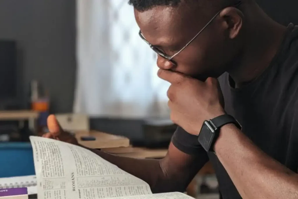 a man wearing black shirt reading the Bible