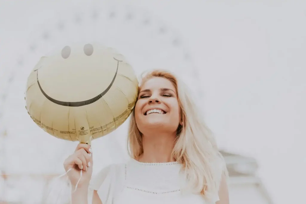 sober girl holding a yellow balloon with smiley design