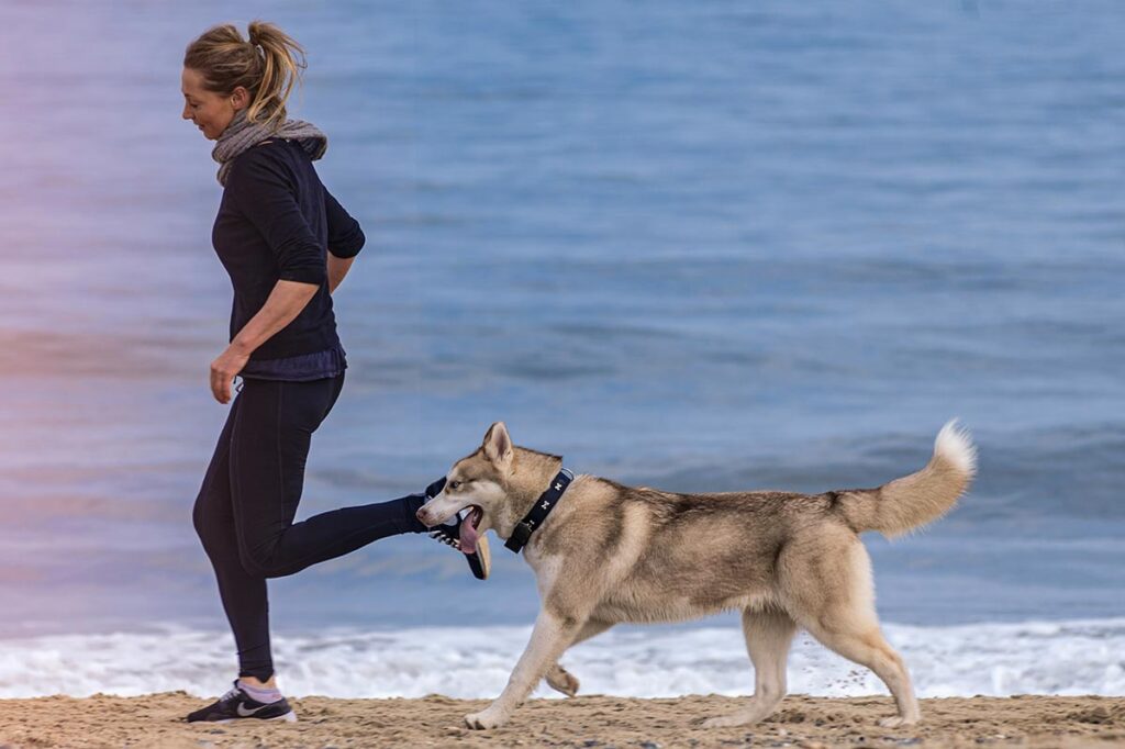 woman running on the beach with her pet near drug and alcohol detox center in southern california