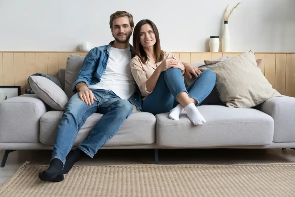 A couple sits on a couch in a living room, participating in a therapy session focused on their relationship during rehab (1)