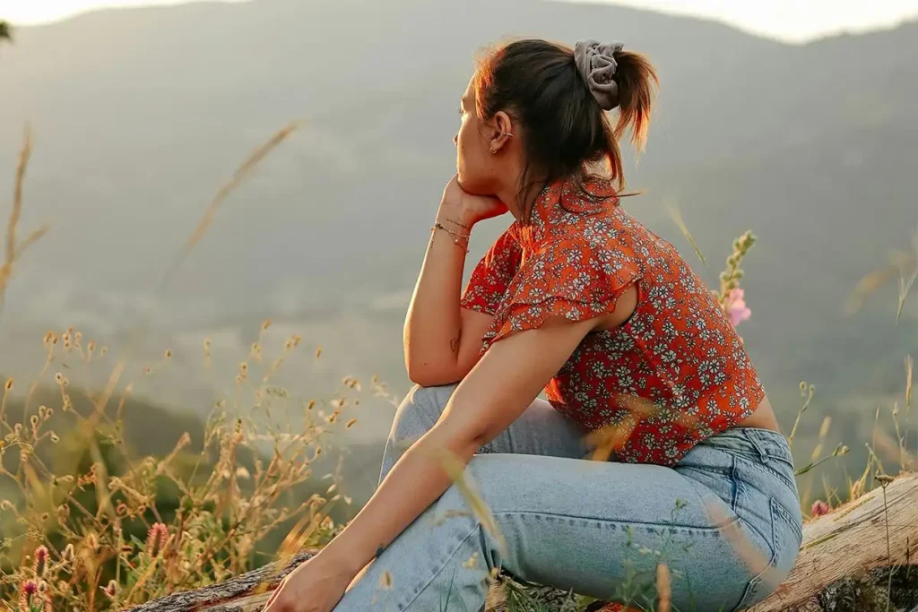 thoughtful woman sitting on top of the hills during sunset