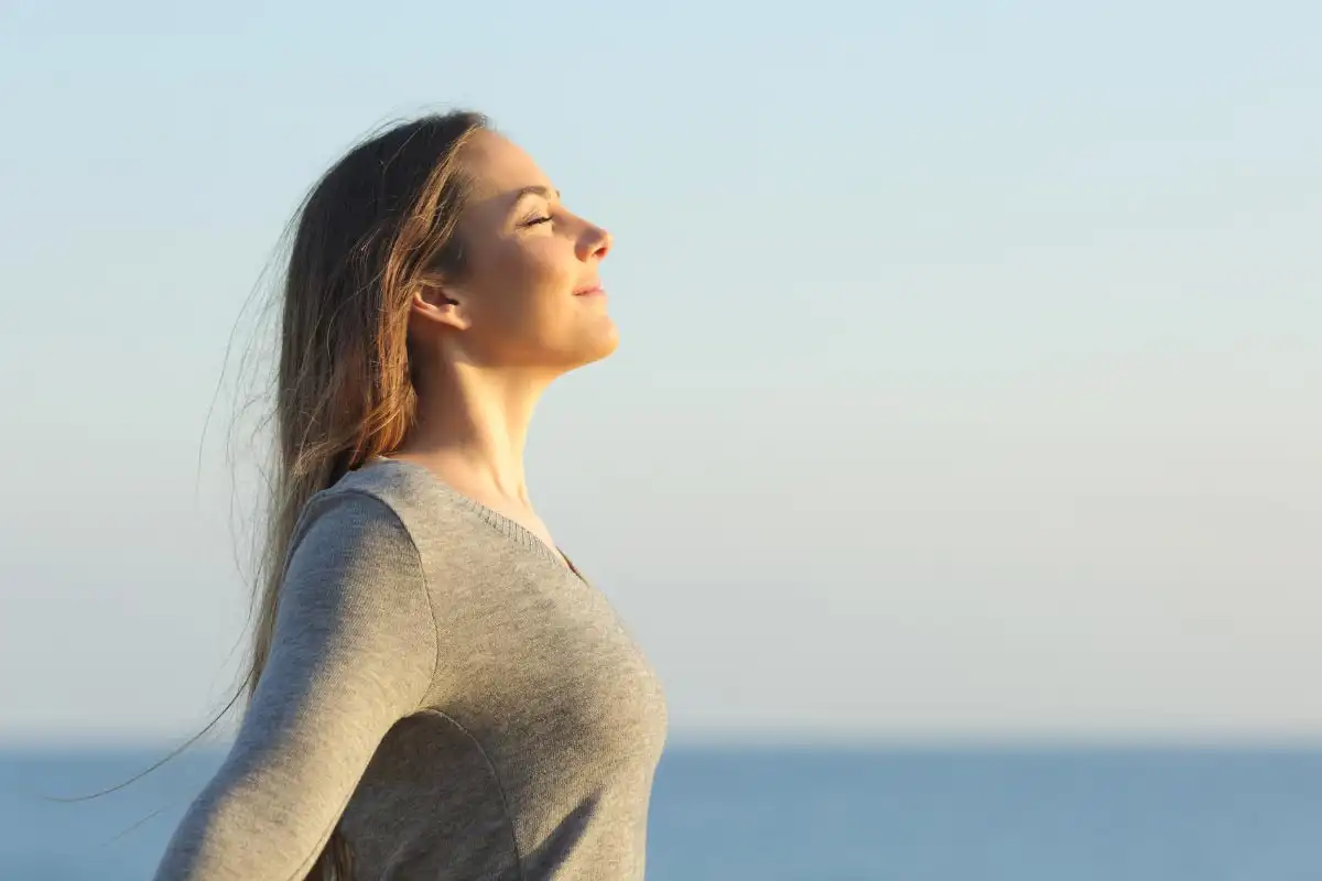 a woman near the ocean taking a moment to breathe