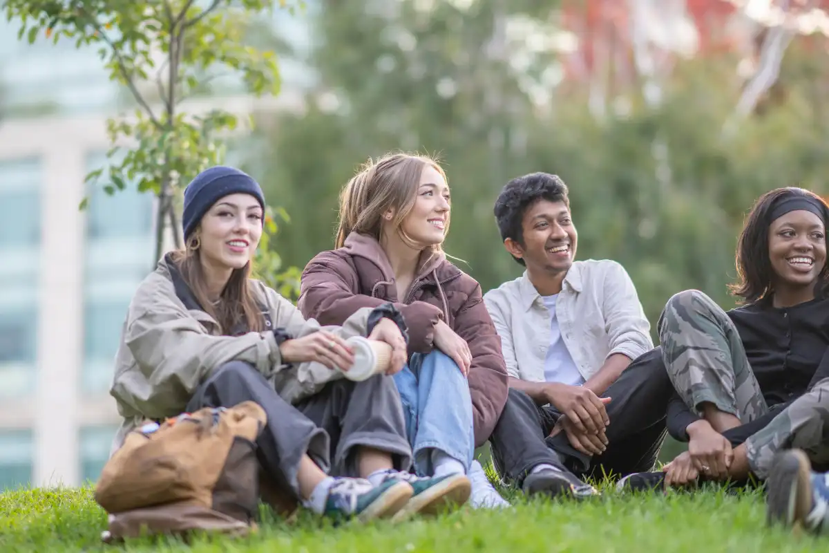 young adults sitting on the grass together outside