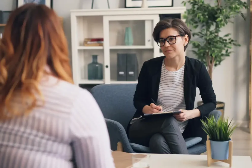 A woman sitting in a chair talking to another woman