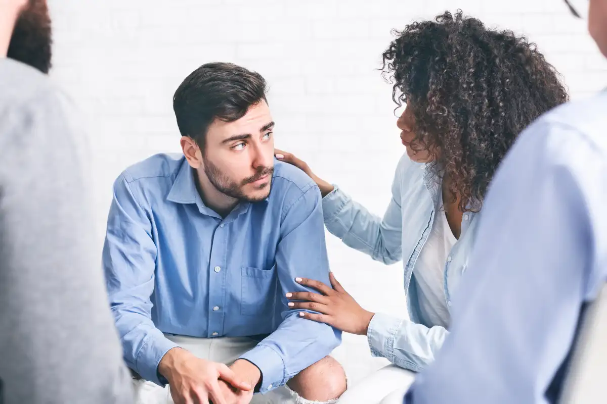 Depressed man getting support from patients of rehab group