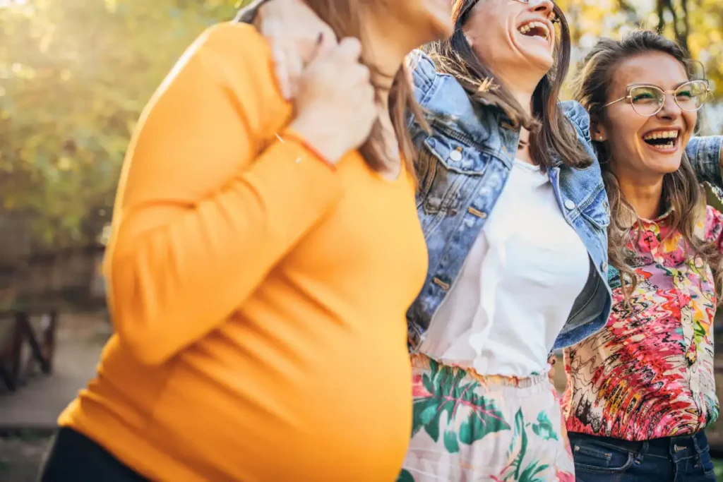 Happy Pregnant Woman with Friends Embracing Each Other from residential treatment center in corona california