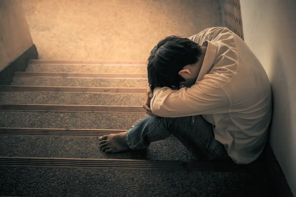 Depressed man sitting head in hands on the stairs in building. with low light environment, dramatic concept, concept of Major depressive disorder