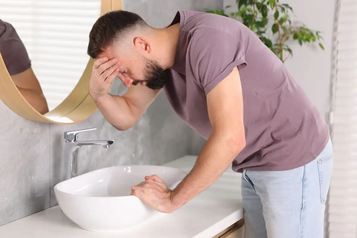 Man Suffering from Nausea over Sink in Bathroom