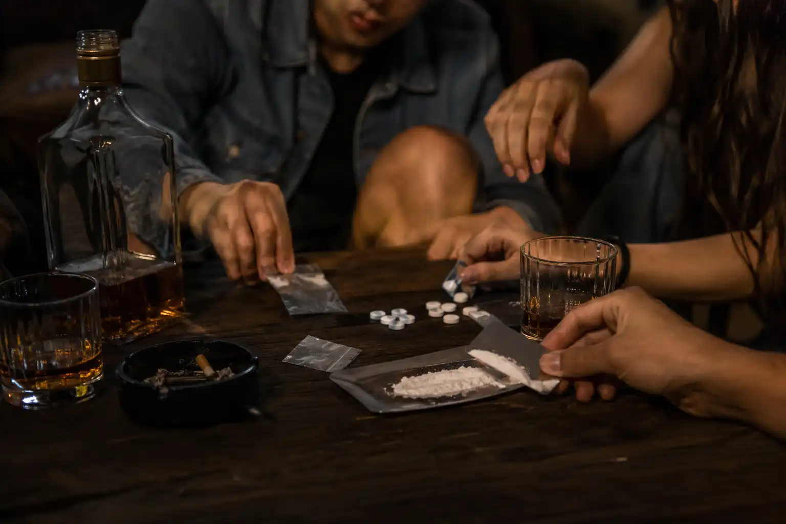 People consuming alcohol while using illicit drugs at a party