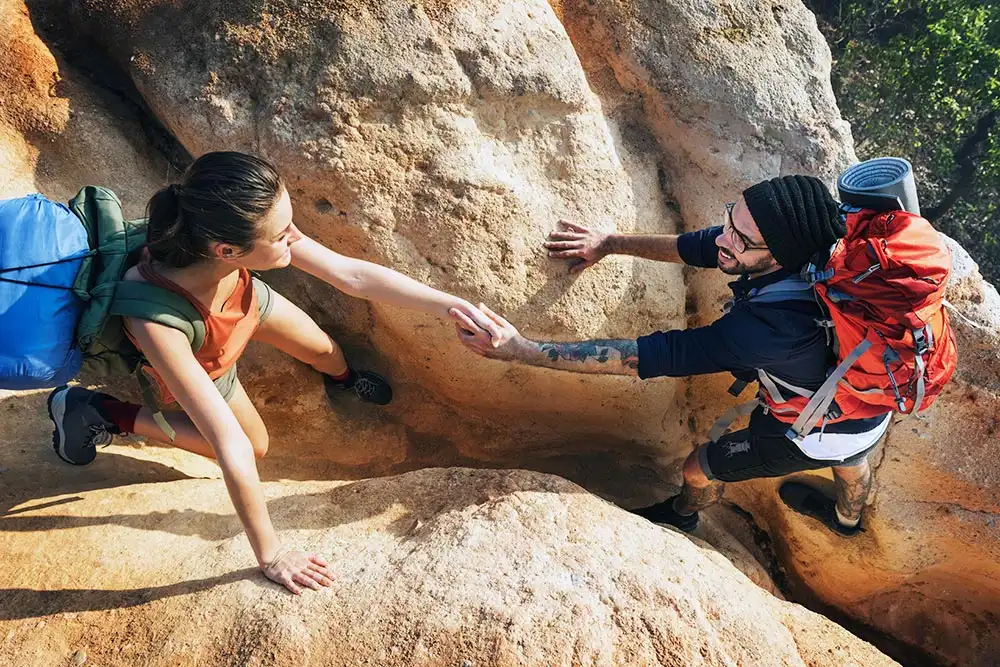 a female and a male climbing rock mountain as part of aftercare program in drug and alcohol rehab in Corona and Southern California